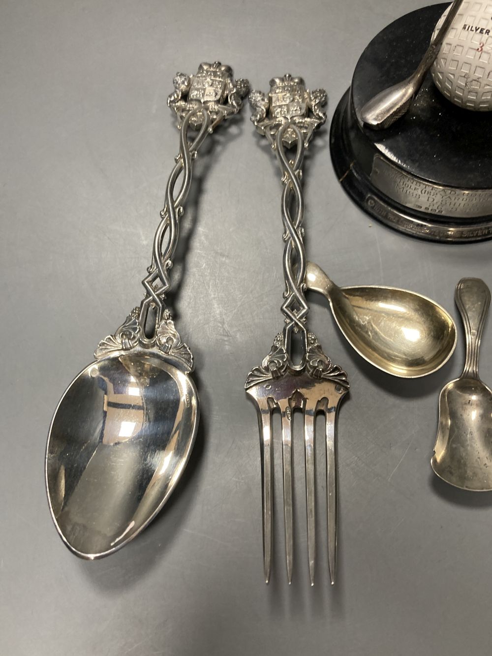 Two 19th century caddy spoons, silver napkin ring, a pair of Continental white metal servers and a golf trophy